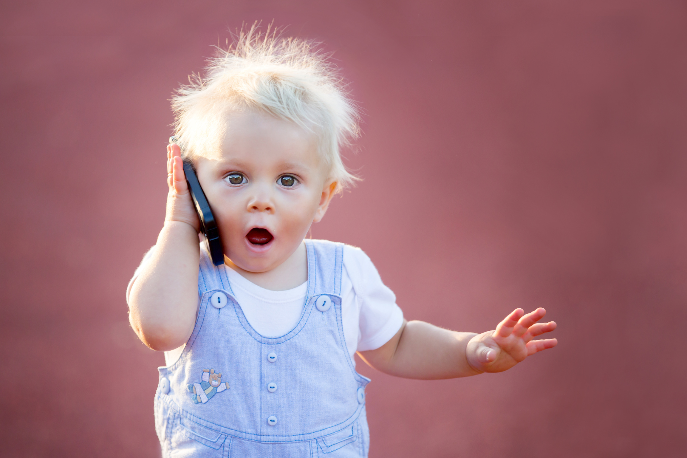 Baby talking on phone with surprised facial expression